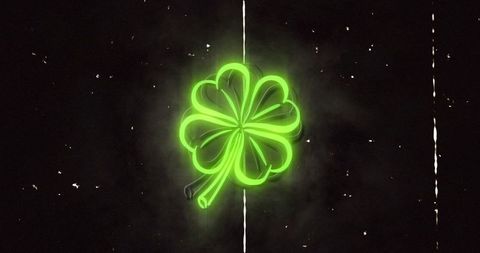 Glowing neon four-leaf clover emblem casting smoky halo on distressed dark backdrop vintage