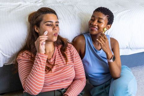 Multiracial women sharing at-home facial care routine with gua sha and gold roller