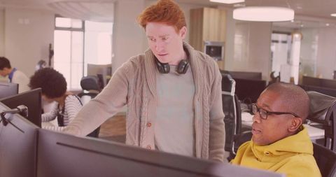 Colleague Guiding Focused Team Member in Modern Office Setting