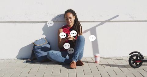 Young woman chatting on smartphone with chat bubbles urban setting