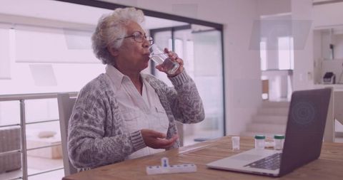 Senior Woman Managing Medication at Home with Laptop