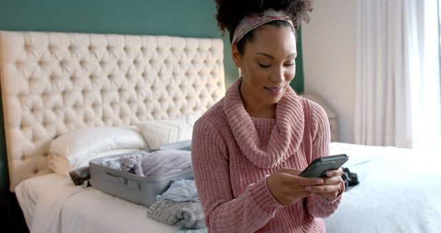 Woman Texting on Phone While Packing for a Trip Bedroom - Download Free Stock Images Pikwizard.com