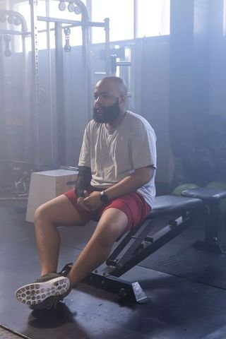 African american man resting on bench between sets in gym calm focused fitness recovery training