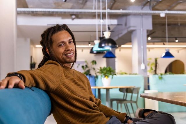 African American Man Checking Wristwatch in Modern Coworking Lounge with Turquoise Accents
