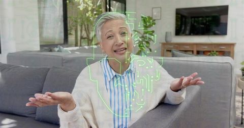 Senior asian woman gesturing during virtual consultation with neon tech hologram overlay