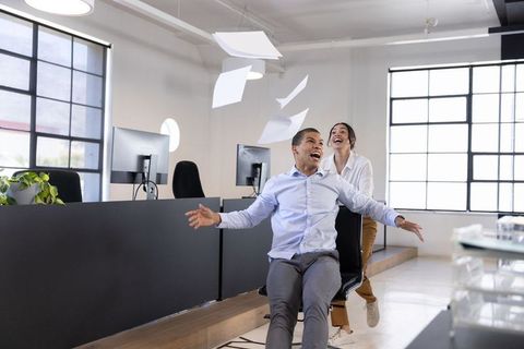 Office workers enjoying chair ride in open workspace