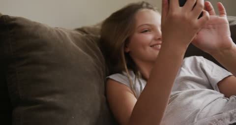 Teenage Girl Relaxing on Sofa Using Smartphone