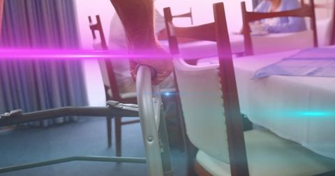 Senior man navigating dining room with walking frame and colorful light streaks