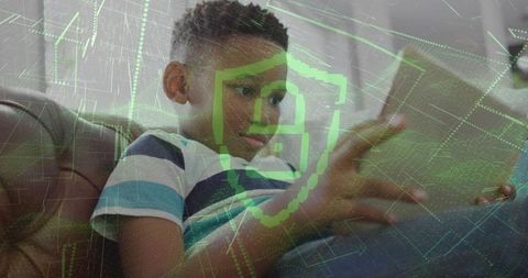 Child using tablet on couch with digital cybersecurity shield overlay and data grid