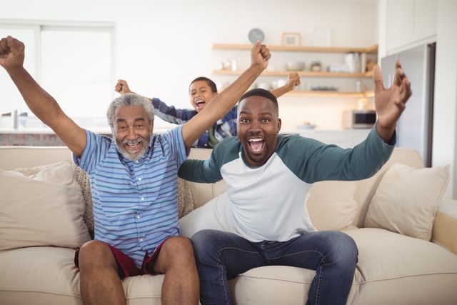 Family members are sitting on a sofa in a living room, enthusiastically cheering while watching television. The scene captures a moment of joy and togetherness, perfect for illustrating themes of family bonding, leisure time, and shared excitement. Ideal for use in advertisements, articles, or social media posts related to family activities, home entertainment, or celebrating special moments.