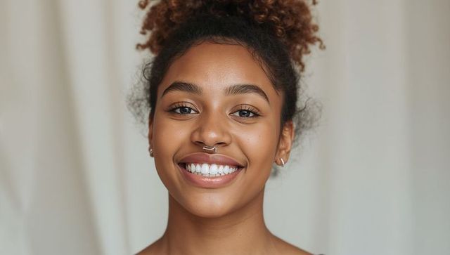Smiling young woman wearing septum ring and curly high bun closeup portrait natural beauty