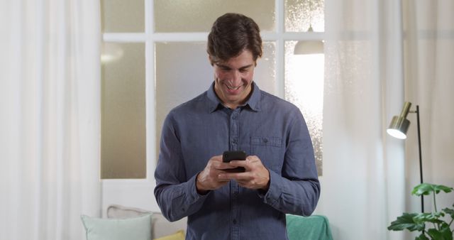 Smiling Man Engaging with Smartphone at Home - Download Free Stock Images Pikwizard.com