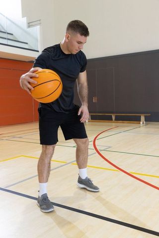 Male athlete practicing ball handling and dribbling on indoor basketball court