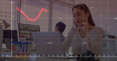 Working woman analyzing data on laptop with red analytics overlay in modern open-plan coworking offi