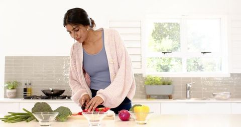 Woman in Bright Kitchen Slicing Fresh Red Pepper
