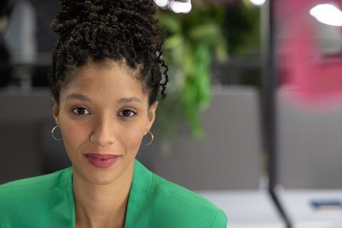 African american woman professional headshot wearing emerald blazer in modern office