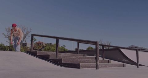 Skater in Red Cap Inspecting Handrail at Urban Skatepark, Concrete Stairs, Sunny Minimal