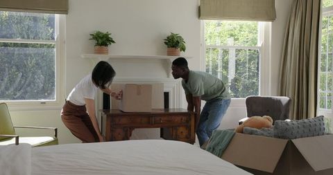 Couple Unpacking Boxes in Sunlit New Home Living Room