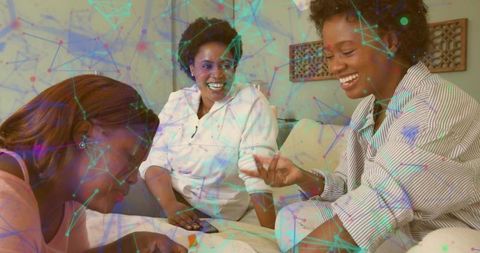 Women Gathering on Sofa Laughing and Collaborating with Digital Network Overlay