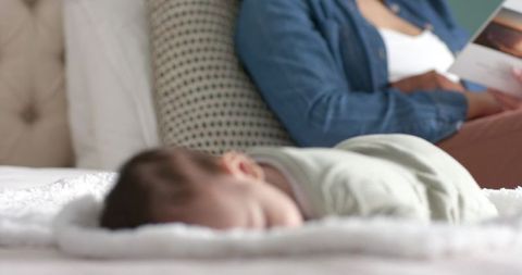 Mother Reading While Infant Sleeps in Cozy Bedroom Scene