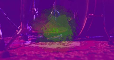 Low-angle bass drum pedal and foot on patterned rug with magenta purple stage lighting