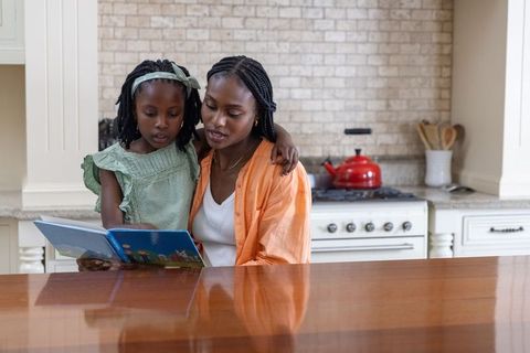 African american mother and daughter reading together at kitchen counter, sharing warm bond