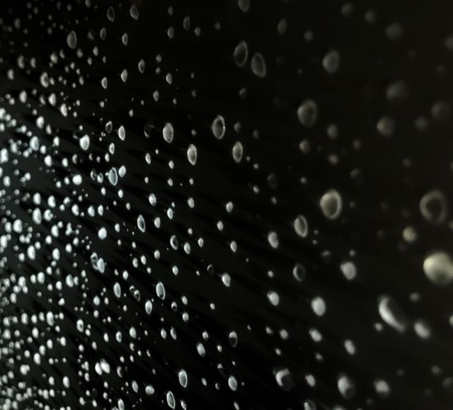 Close-up of many water droplets on black background. Shows droplets' delicate, spherical shapes, highlighting texture and contrast. Ideal for backgrounds, abstract designs, and water-related projects.