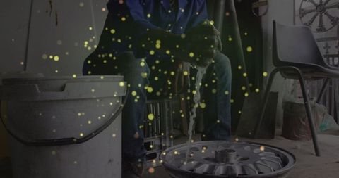 Mechanic scrubbing car wheel rim in garage workshop setting