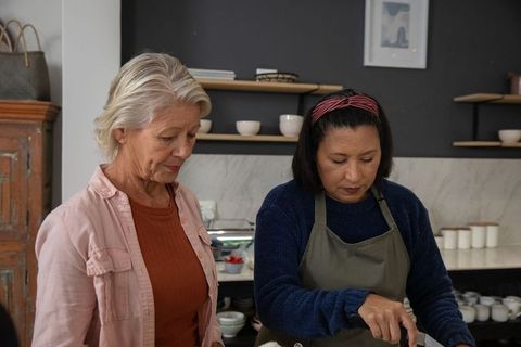 Two generations cooking together in modern kitchen mentoring and teaching culinary skills