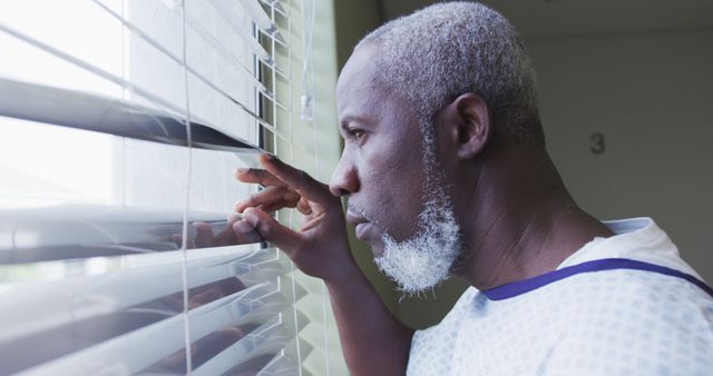 Elderly Man in Hospital Gown Looking Through Window Blinds - Download Free Stock Images Pikwizard.com