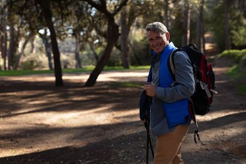 Senior male hiker enjoying peaceful nature walk with backpack and trekking poles