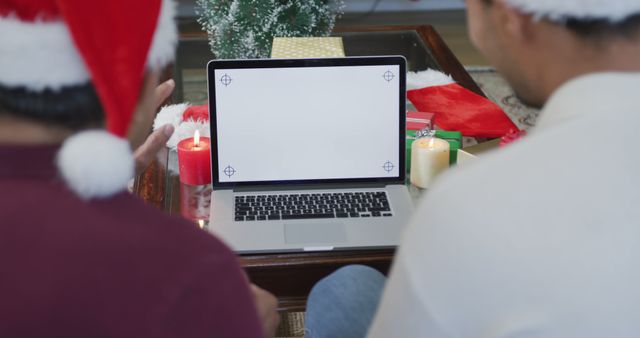 Happy son and father making christmas image call on laptop with blank white screen and copy space. christmas, festivity and communication technology.
