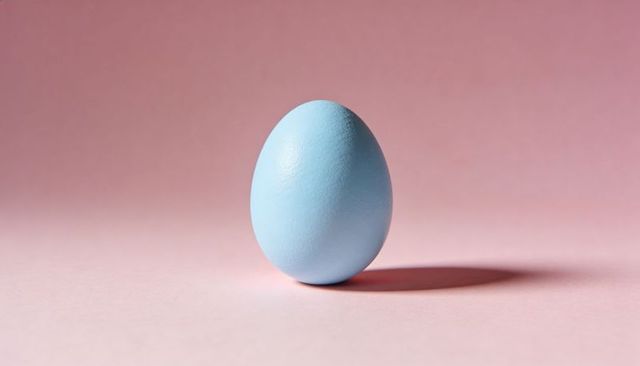 Light-blue egg standing on pastel-pink surface casting soft shadow for minimalist design