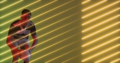 Male basketball player holding ball amid diagonal neon lights, dynamic sports concept