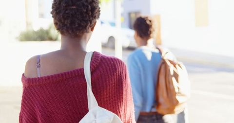 Twin Teenage Sisters Walking Outdoors with Backpacks