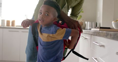 Grandfather Helping Grandson with Schoolbag in Kitchen Morning Routine