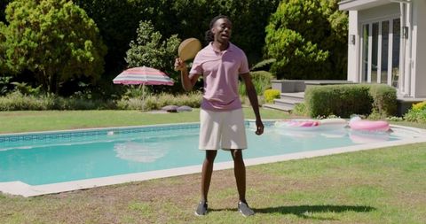 Man enjoying vibrant paddle ball game near backyard pool