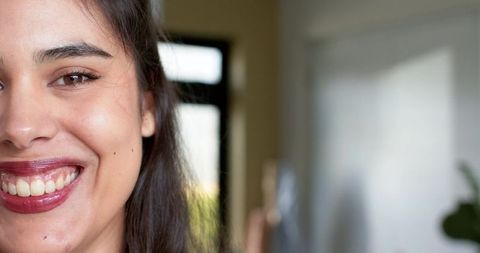 Smiling woman closeup showing glossy dark lipstick and natural skin in soft window light