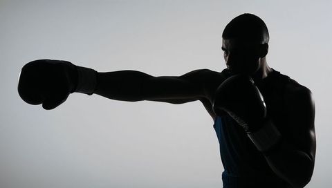 Backlit boxer delivering powerful straight jab silhouette for sport and fitness branding