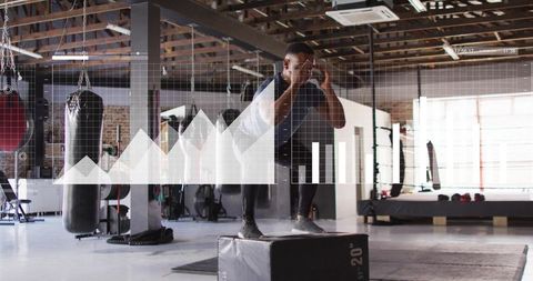 Athlete performing plyometric box jump in industrial gym with digital performance hud overlay