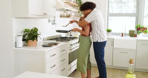 Diverse Couple Cooking Together in Modern White Kitchen