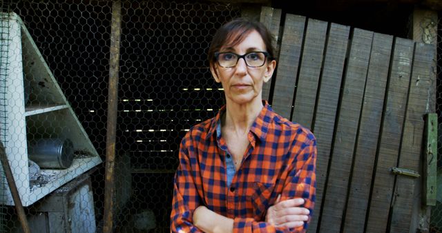 Serious woman standing with arms crossed in front of rustic wooden backdrop - Download Free Stock Images Pikwizard.com