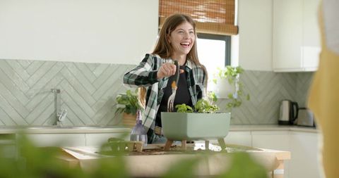 Young woman planting herbs on kitchen island wearing green flannel, natural light lifestyle