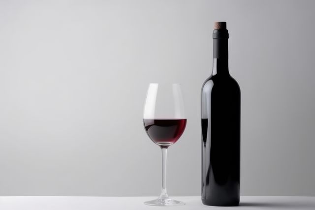This visual showcases an elegant red wine bottle next to a half-filled wine glass against a clean white background. Ideal for use in advertising campaigns for wine brands, blogs about fine dining and wine tasting experiences, restaurant menus, or promotional materials for celebrations and special occasions.