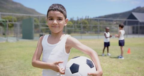 Young Boy Holding Soccer Ball on School Field
