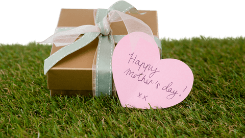 Transparent gift box with heart tag for mother's day on grass