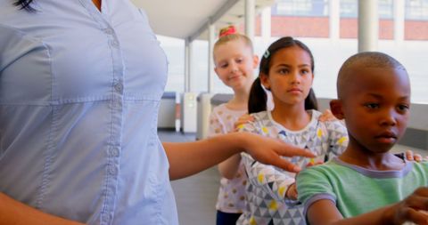 Teacher and Diverse Schoolchildren Lining Up in School Corridor