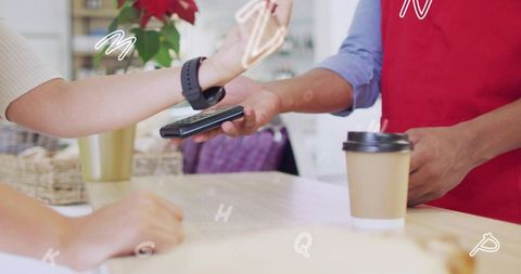 Contactless smartwatch payment at coffee counter, barista holding mobile card reader