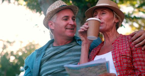 Smiling Elderly Couple Enjoying Outdoors with Coffee and Map