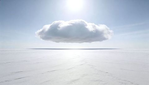 Cumulus hovering over reflective salt flat creating sun halo and minimalist horizon